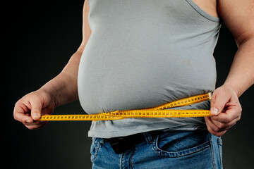 man with a fat belly with scales in his hands on a dark background