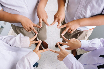 Asian students put their hands together in a fun gesture to get ready to complete the mission successfully.