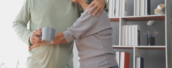 Happy old couple holding cup of hot tea while enjoying leisure time together at the home