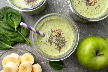 Detox spinach drink with green apple and banana, on a gray concrete background in glasses, top view
