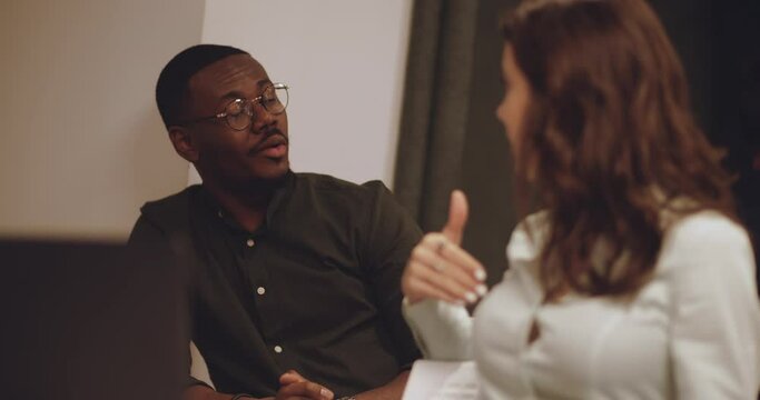 Diverse international people are chatting on different tables and working together to solve the challenges