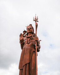 The giant Shiva statue of Durga at the Hindu temple Ganga Talao, Grand Bassin, Mauritius. close-up shot with blue sky. 