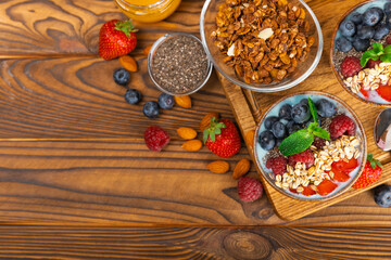 Bowl of granola with yogurt and fresh berries on a texture table. Yogurt berries, acai bowl, spirulina bowl. Healthy food, balanced breakfast. Strawberries, blueberries, kiwi, peach, almonds and chia.