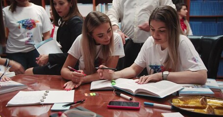 Group of diverse college students consulting with professor in the library setting. University education concept - Powered by Adobe