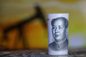 Chinese yuan banknote on oil pump rig background. Concept of oil industry and prices