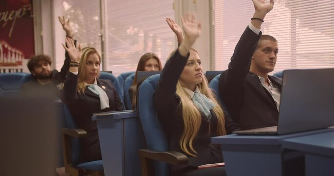 Students at class listening to lectures and raising hands to answer