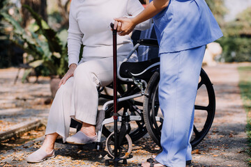 Obraz premium Asian young woman nurse at nursing home take care disabled senior man. Caregiver doctor serve physical therapy for older elderly patient to exercise and practice walking on walker or cane at backyard.
