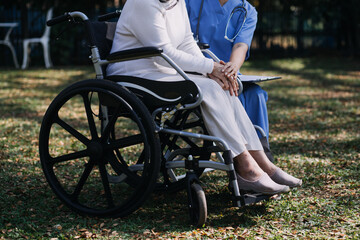 Fototapeta premium Asian young woman nurse at nursing home take care disabled senior man. Caregiver doctor serve physical therapy for older elderly patient to exercise and practice walking on walker or cane at backyard.
