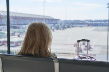 silhouette of an unrecognizable middle-aged woman sitting looking out of the glass of an airport terminal