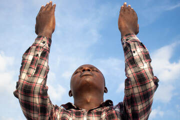 An inspiring depiction of a Christian pastor, his hands open and raised skyward, his profile bathed...