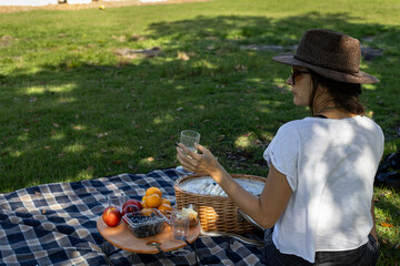 Woman sitting with hat at picnic in park