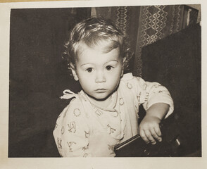 USSR, Leningrad. Vintage photo of July 1983. A small one-year-old child looks up at the camera with curiosity