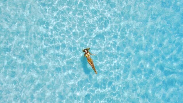 Woman floating and relaxing in blue ocean. Aerial view, top view.