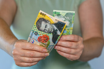 Romania money, Woman holds 200 lei and 1 lei banknotes in her hands, Financial concept