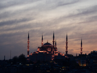 Pboto of mosque lit up after sunset on Istanbul skyline 