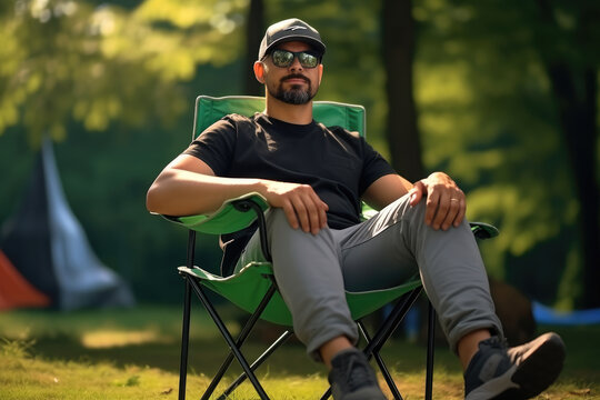 Picture of man sitting in green chair placed on grass. This image can be used to depict relaxation, outdoor seating, or enjoying nature.