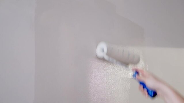 Painter man painting the wall white with a roller