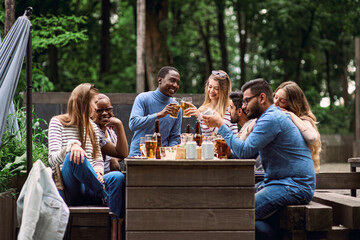 Clinking beer glasses. A company of multicultural friends is celebrating a holiday outside in...