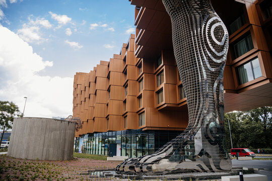 Prague, Czech Republic, 16 July 2023: Huge female statue of naked woman, Lilith by David Cerny in Karlin district supporting fragment of residential building, leg and hand, stainless steel, modern art