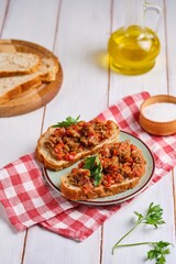 Two sandwiches with eggplant caviar made from baked eggplants, sweet peppers and tomatoes, seasoned with vegetable oil, on a green clay plate on a white wooden background.