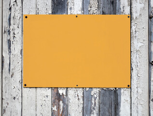 Blank yellow sign on a wooden fence.