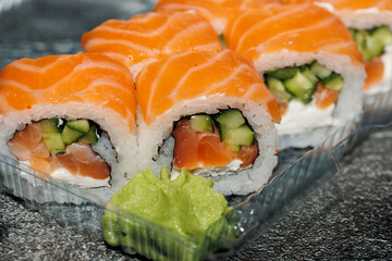 Sushi roll with salmon, avocado, smoked eel, cream cheese on a black background. Japanese food.