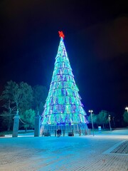 vertical image of a big christmas tree with blue lights decorating the streets at christmas