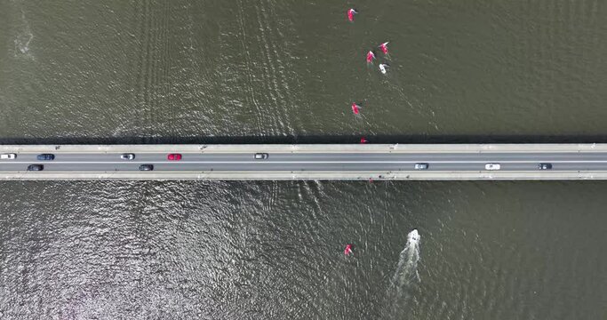 Sailboats compete in a summer race by sailing under a road bridge 4k
