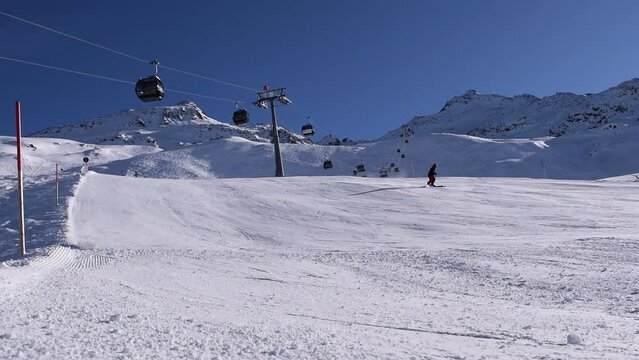 Active skiers and snowboarders descending a mountain slope on beautiful sunny day. Quiet ski slope in Hochgurgl ski resort, located in the Austrian alps.