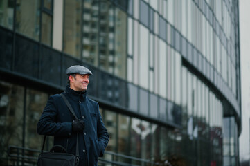 Businessman is standing in front of the corporate firm downtown on a cold rainy day.