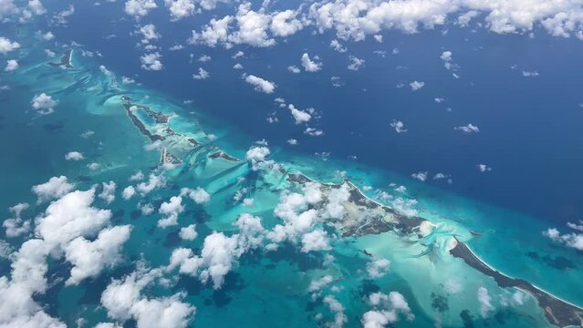 Aerial view of islands in Caribbean Sea displaying vibrant green and blue waters with white clouds. Travel or vacation concept in 4K video format.  