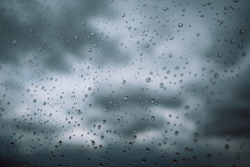 Window with small raindrops on the surface of a glass against a blue cloudy sky after a storm. Weather forecast. Rainy season. Fall or spring cold day. View of the sky from the window. Air concept.
