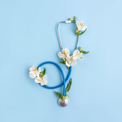 Stethoscope and astroemeria flowers on blue background. Medical banner. Happy doctor's day concept. Square orientation, selective focus
