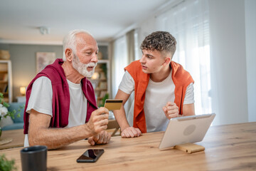 teenager and senior man grandfather use credit card shopping online