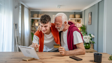 teenager and senior man grandfather use credit card shopping online