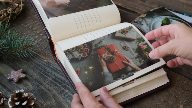 Christmas photo printing. Woman looks through photo album with printed photos. 