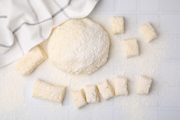 Fototapeta na wymiar Making lazy dumplings. Raw dough and flour on white tiled table, flat lay