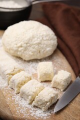 Fototapeta na wymiar Making lazy dumplings. Raw dough, flour and knife on wooden board, closeup