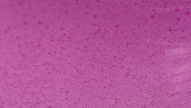 Bright pink foam in the washing machine drum, abstract liquid background, fuchsia bubbles texture
