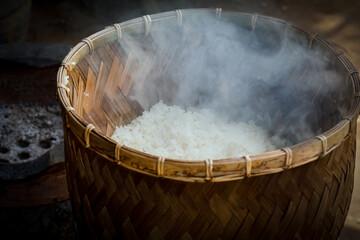steaming sticky rice on earthen steamer, sticky rice cooking on charcoal stove. Sticky rice is also...