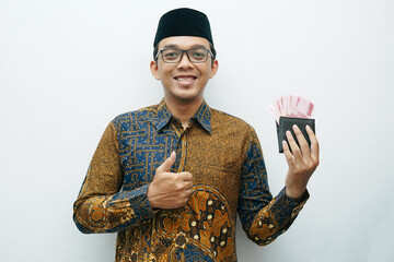 Portrait of Asian Indonesian man in Batik traditional shirt showing wallet with full of rupiah money banknote - obrazy, fototapety, plakaty