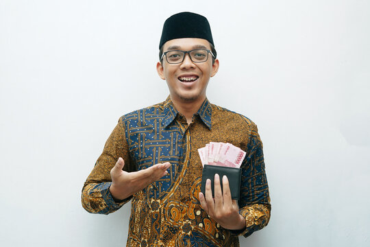 Portrait of Asian Indonesian man in Batik traditional shirt showing wallet with full of rupiah money banknote