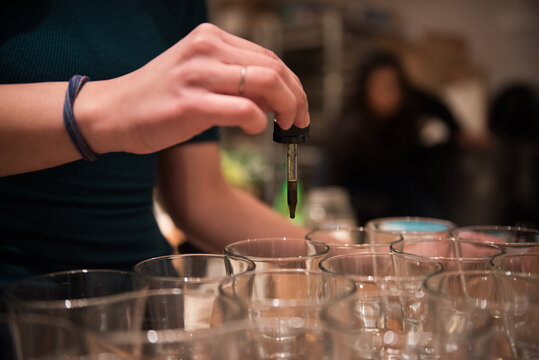 Person putting drops of THC tincture into glasses
