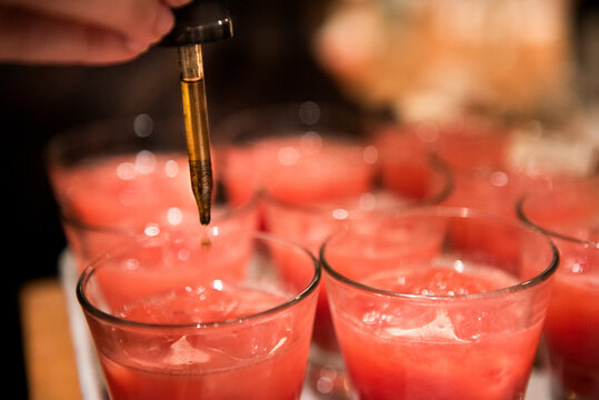 Person putting drops of THC tincture into cocktails
