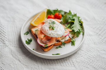 Breakfast toast, cucumber, salmon, poached eggs, and vegetables.