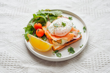 Breakfast toast, cucumber, salmon, poached eggs, and vegetables.