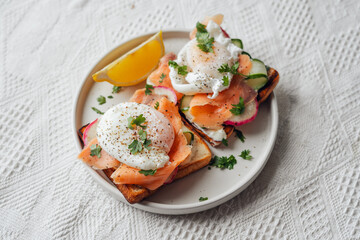 Breakfast toast, cucumber, salmon, poached eggs, and vegetables.