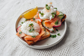 Breakfast toast, cucumber, salmon, poached eggs, and vegetables.