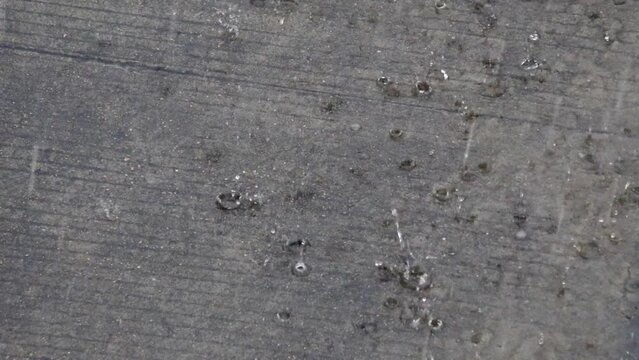 Heavy rain falls on the concrete floor.