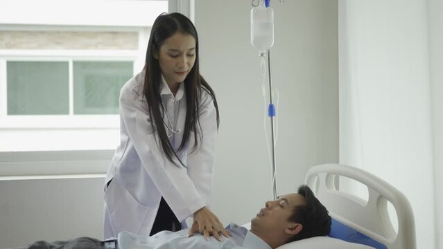Asian female doctor gives first aid to a cardiac arrest patient by performing CPR on a hospital bed. The doctor uses a hand pump on his chest to provide first aid. CPR medical concept